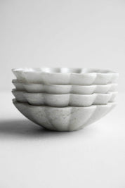 Side view of stacked marble dishes highlighting scalloped edges
