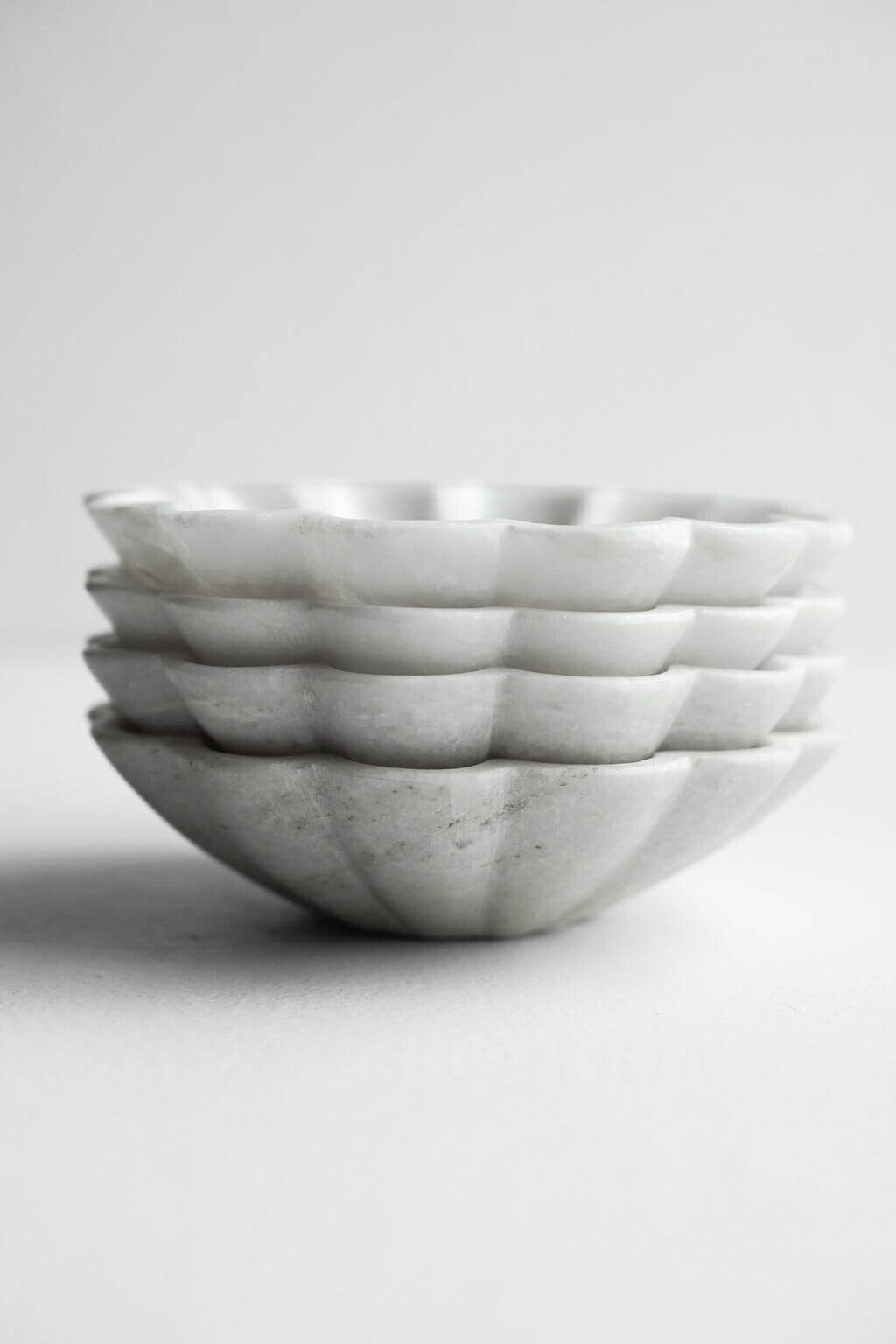Side view of stacked marble dishes highlighting scalloped edges