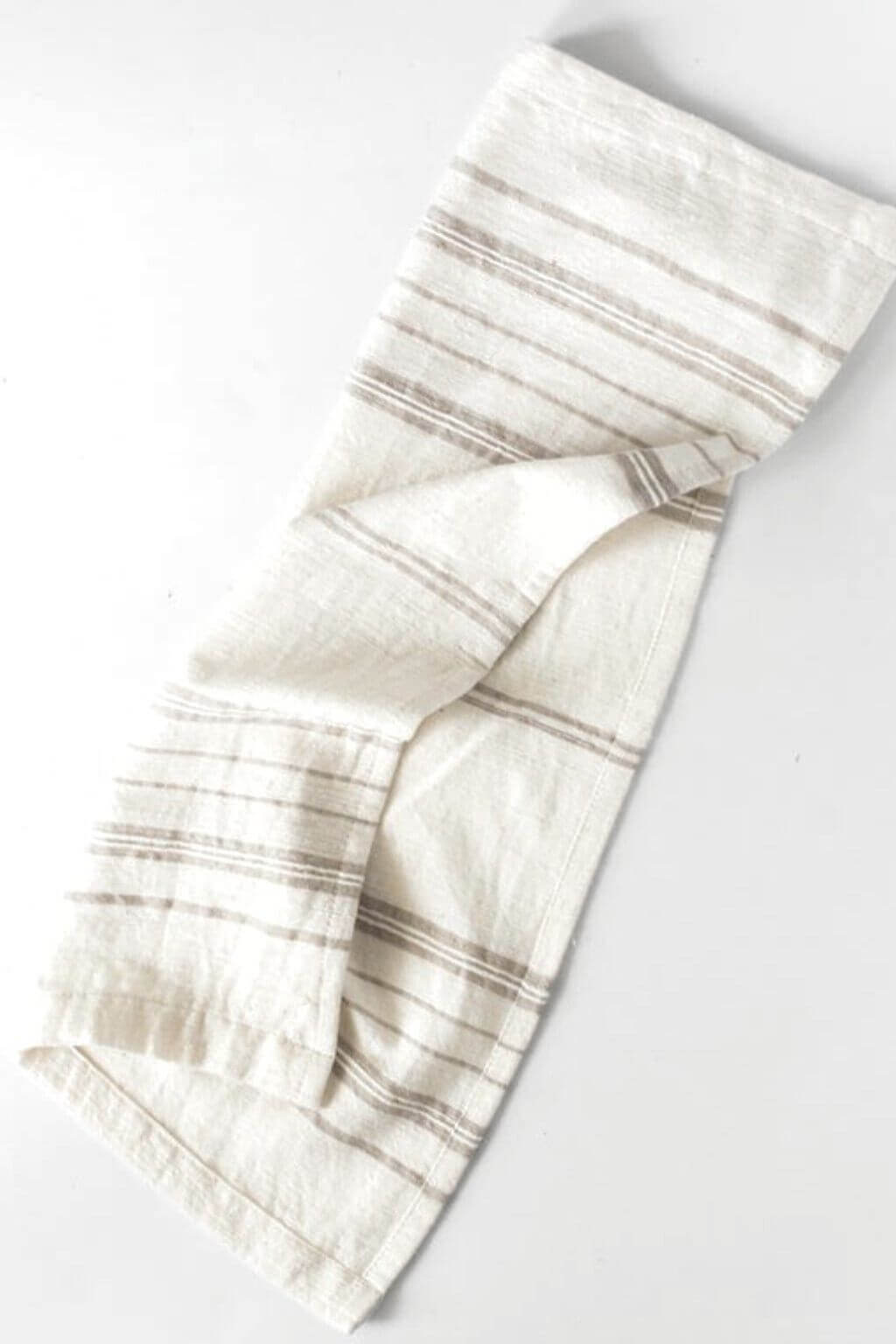 Striped light grey folded tea towel on a white background