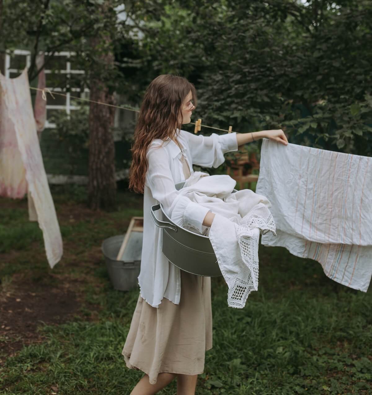 Woman hanging laundry on a clothesline in a garden