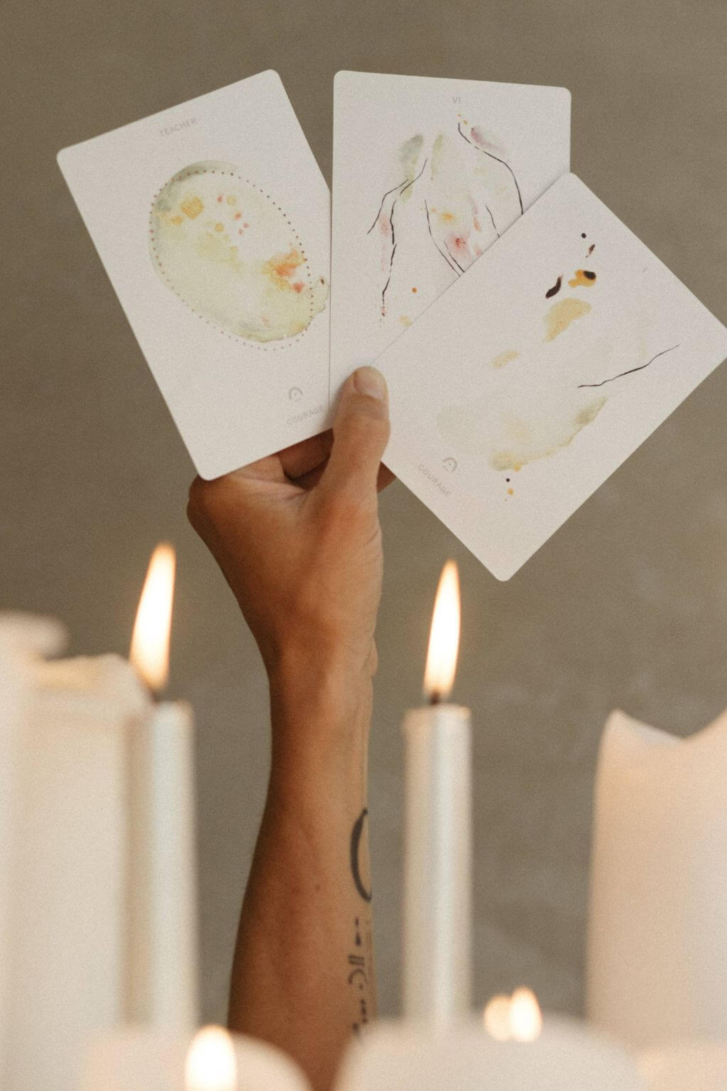 hand holding the depths tarot cards above lit ritual candles