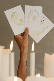 hand holding the depths tarot cards above lit ritual candles