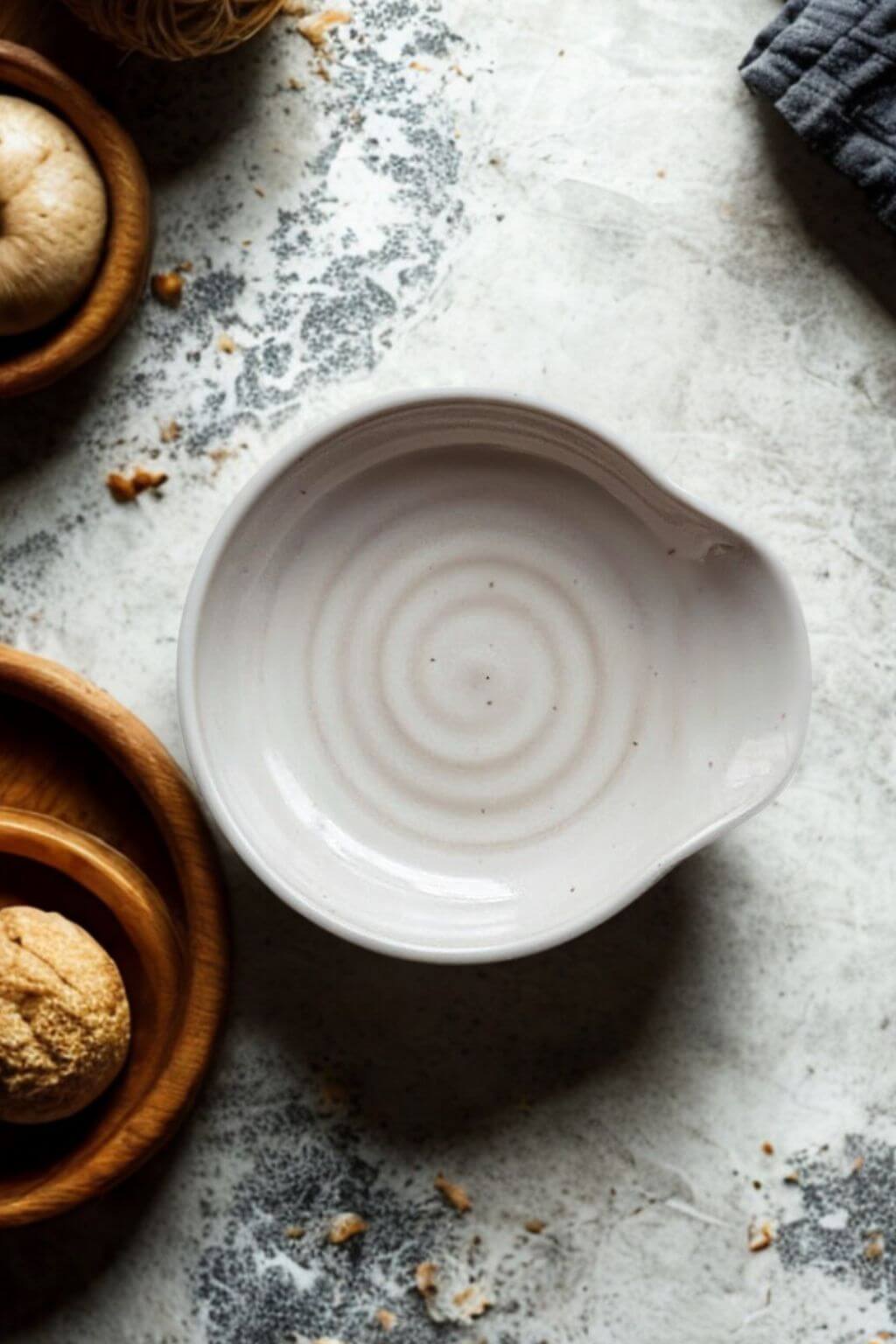 artisan ceramic spoon rest surrounded by wooden bowls and baking ingredients