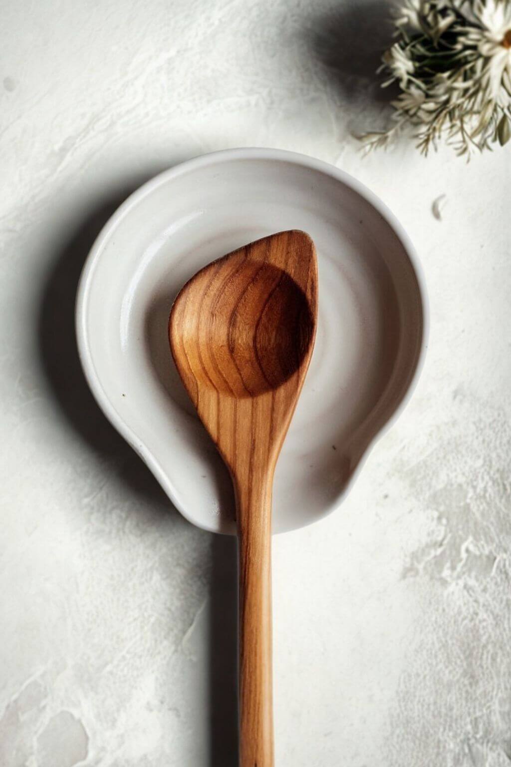 handmade ceramic spoon rest with wooden spoon on neutral surface