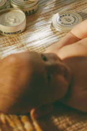 Baby care moment with Dr. Max’s diaper ointment on quilted blanket