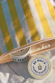Dr. Max’s diaper ointment tins in striped pouch with natural baby care essentials