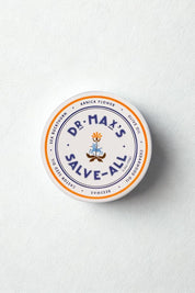 Tin of Salve-All styled on soft, textured background