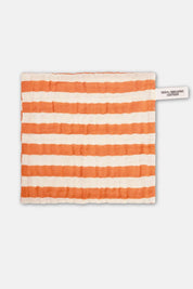 flat lay of orange striped organic cotton washcloth with textured cotton weave