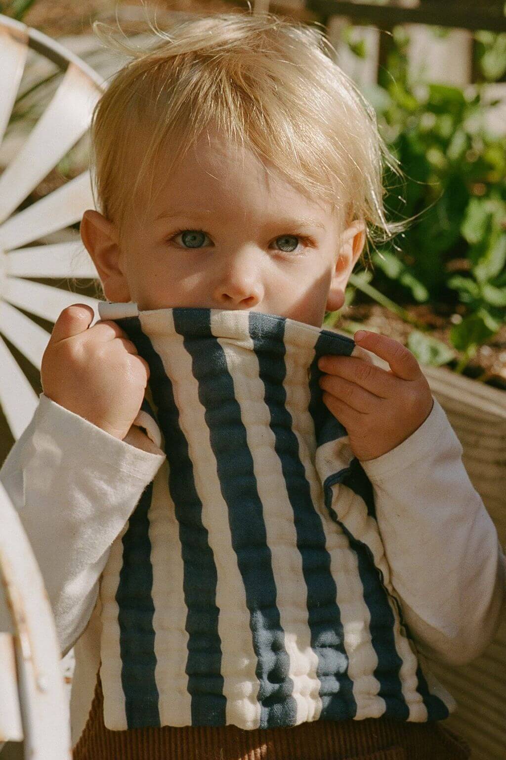 child holding green striped organic cotton washcloth outdoors