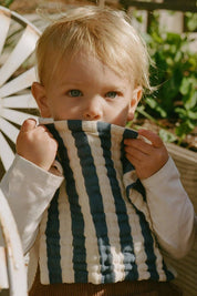 child holding green striped organic cotton washcloth outdoors