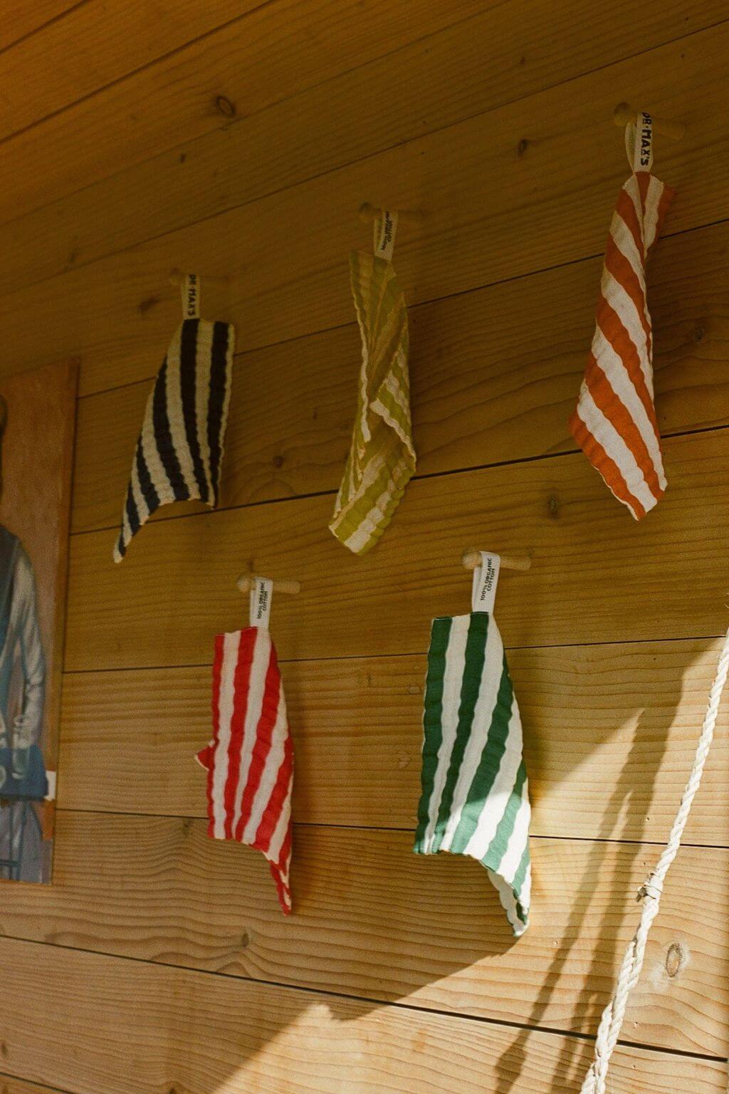colorful striped organic cotton washcloths hanging on wooden wall in natural light