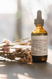 evergreen apothecary goodbye metals herbal tincture bottle with dried florals in warm light