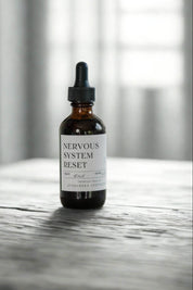 evergreen apothecary nervous system reset tincture bottle on stone surface with soft light