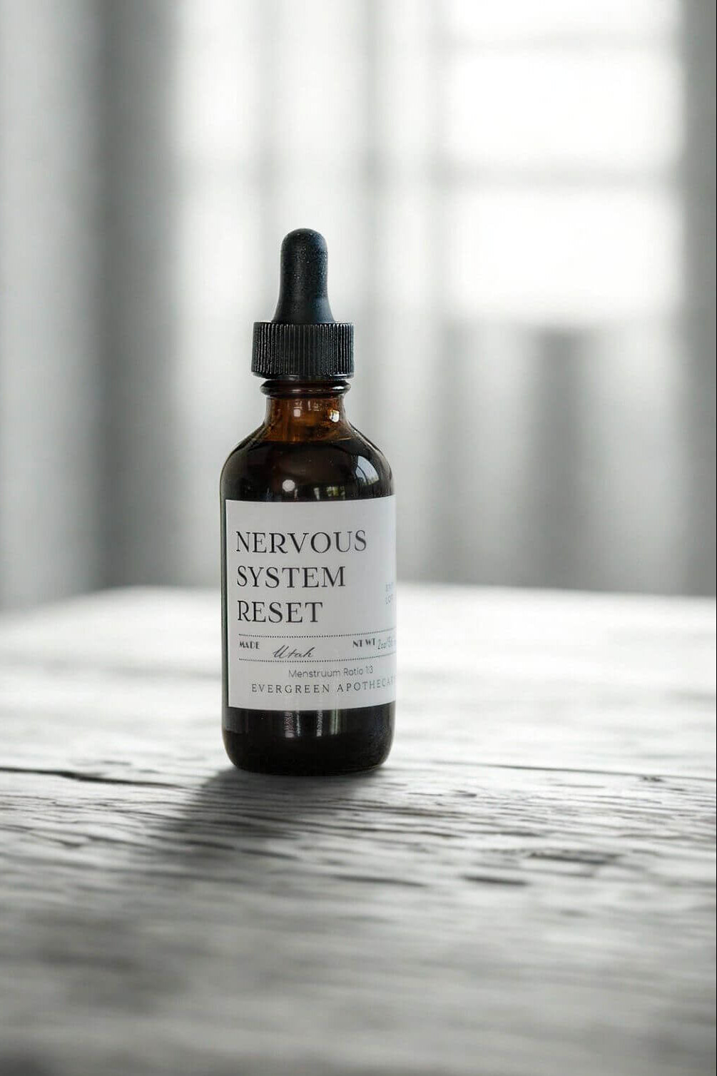 evergreen apothecary nervous system reset tincture bottle on stone surface with soft light