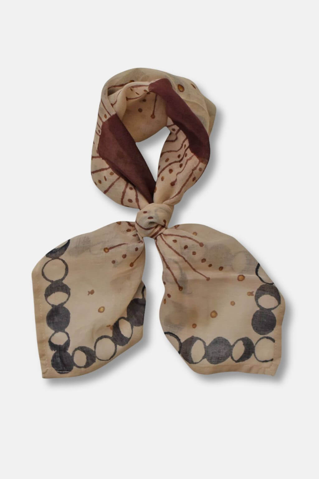 Beige scarf with circular patterns tied into a knot on a white background