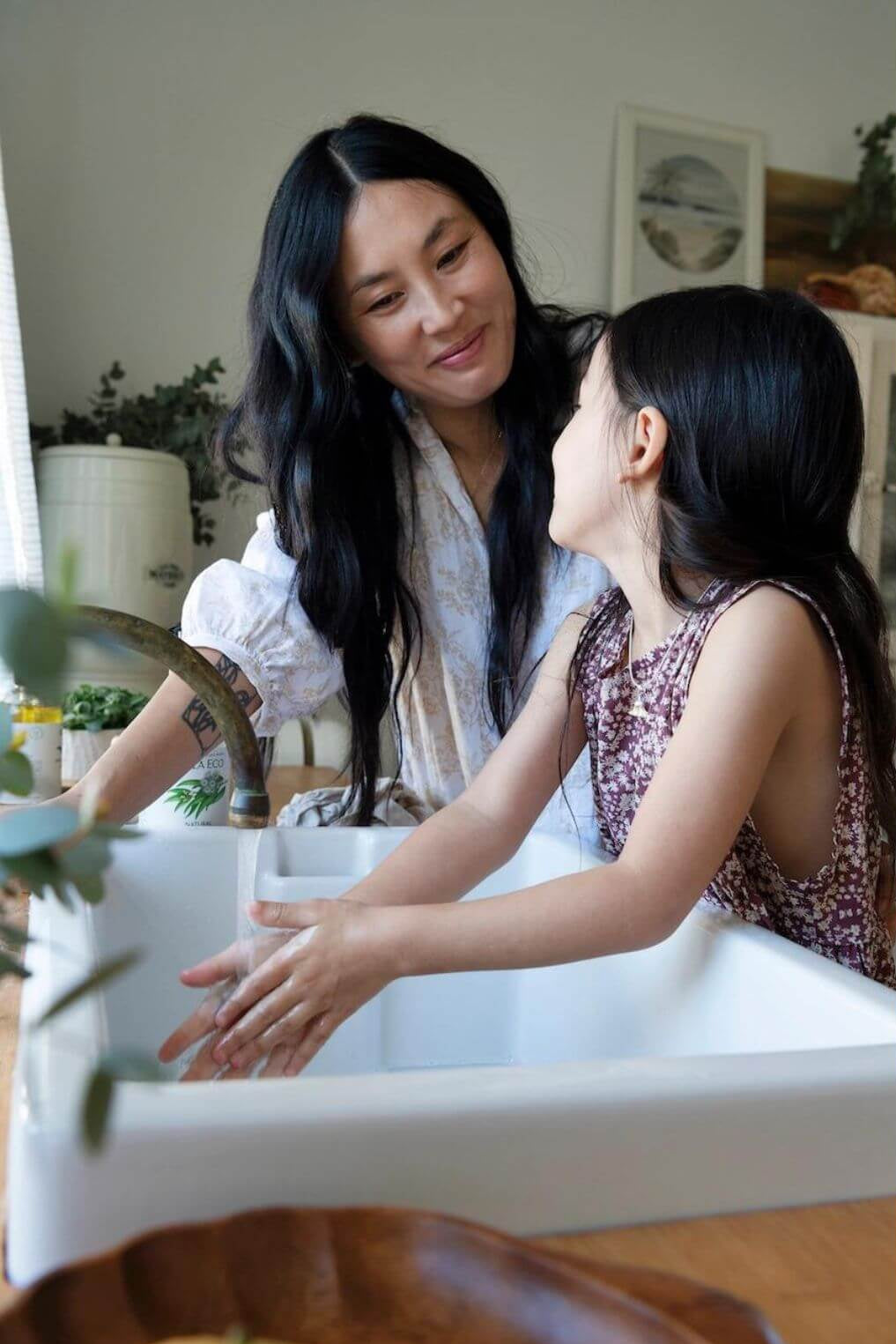Woman and child washing hands in a sink with a neutral background