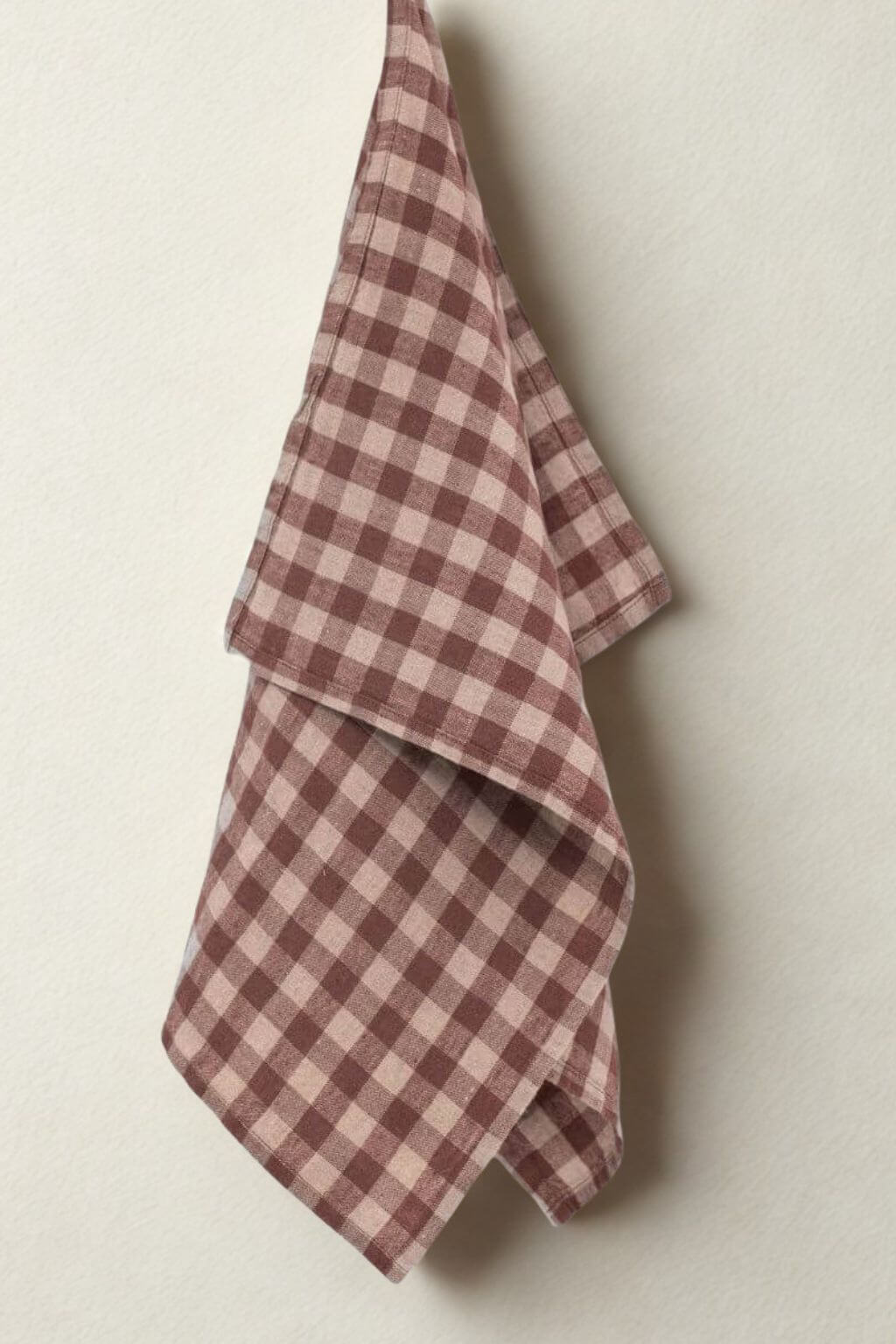Chocolate gingham linen kitchen towel hanging against neutral wall