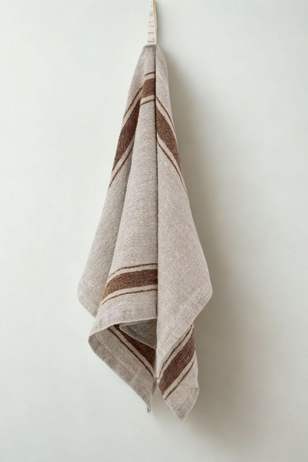 Heavyweight mocha stripe linen kitchen towel hanging on a light colored wall