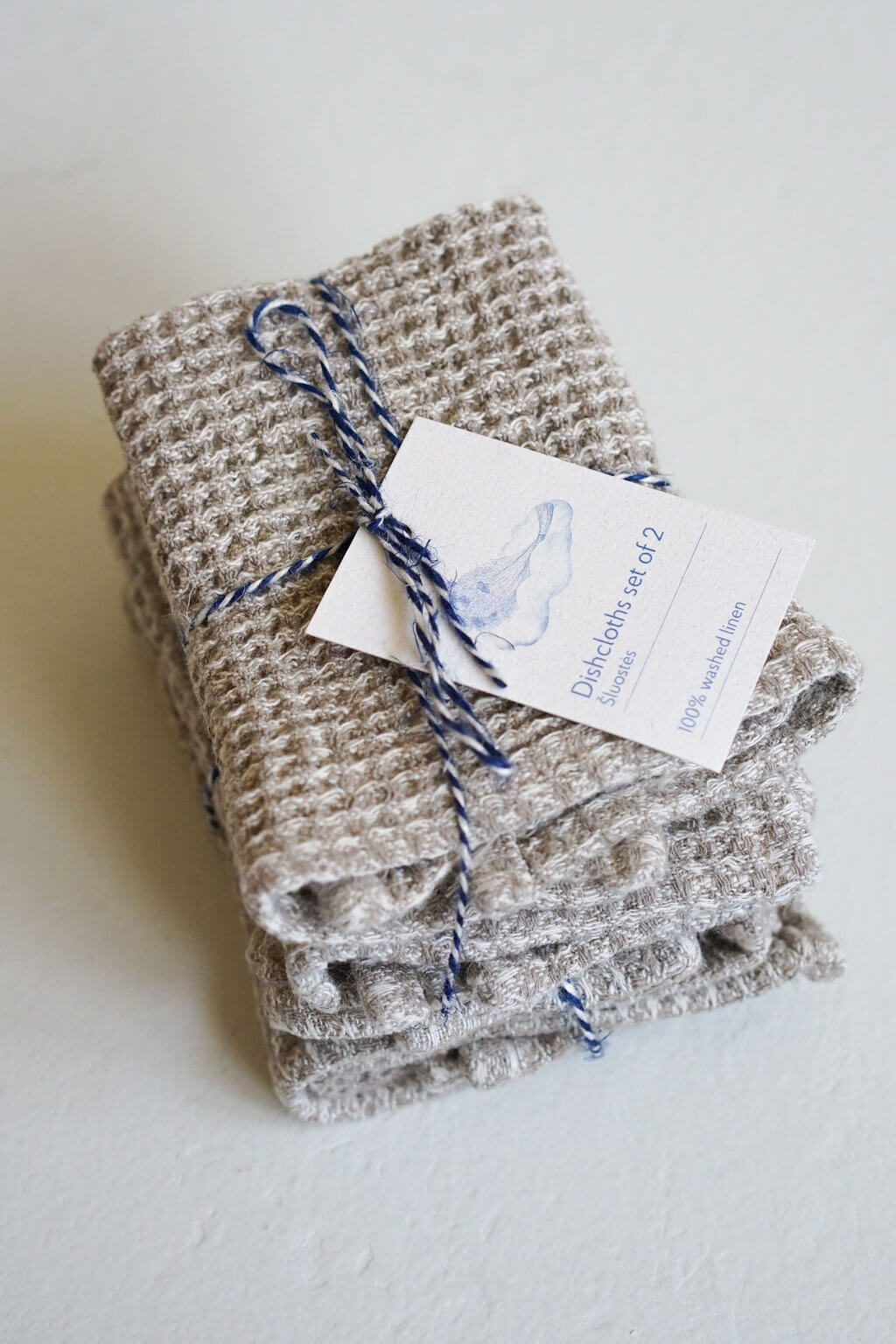Folded natural linen waffle dishcloth set with artisan product tag