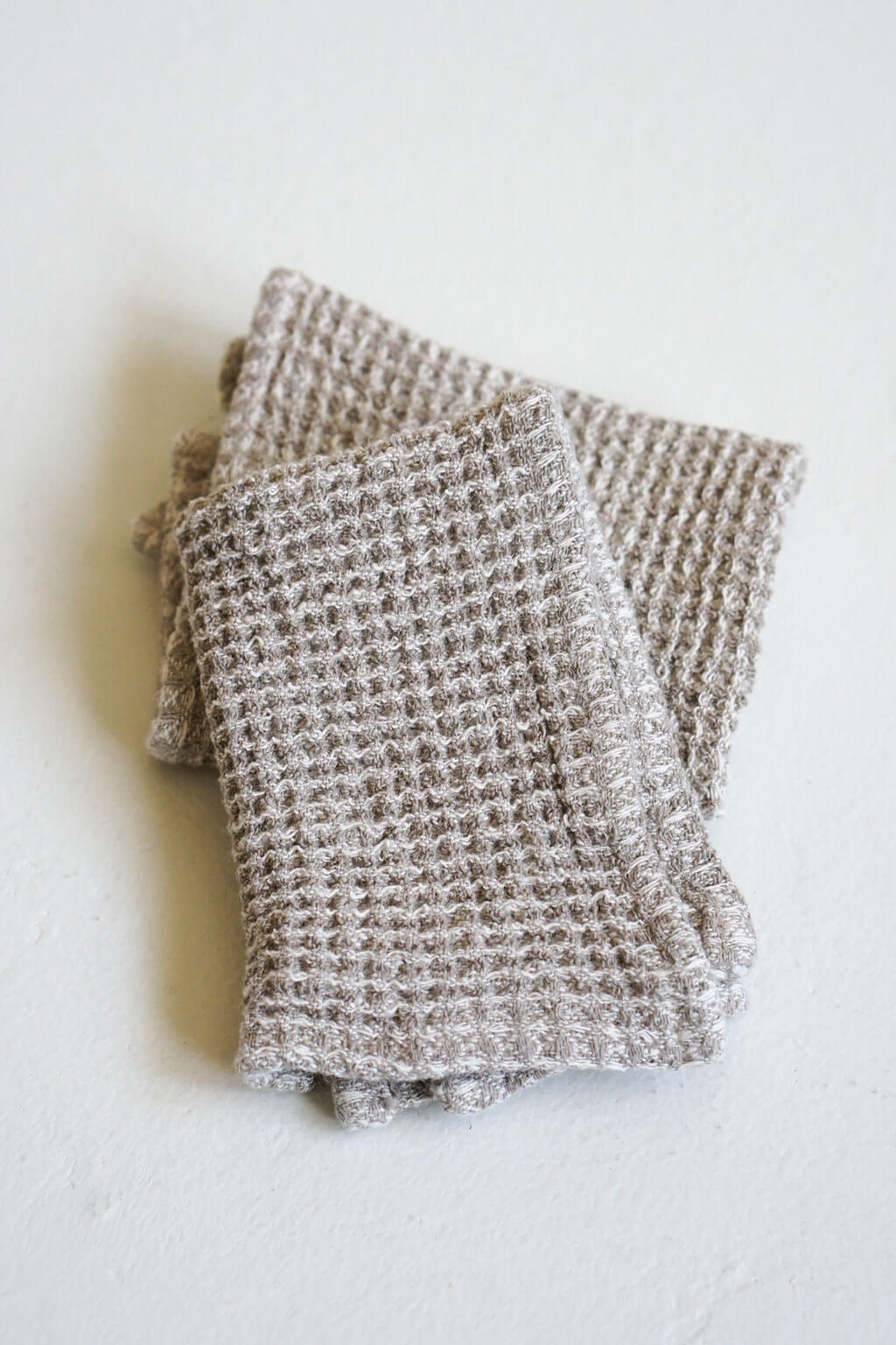 Folded natural linen waffle dishcloth set on neutral background