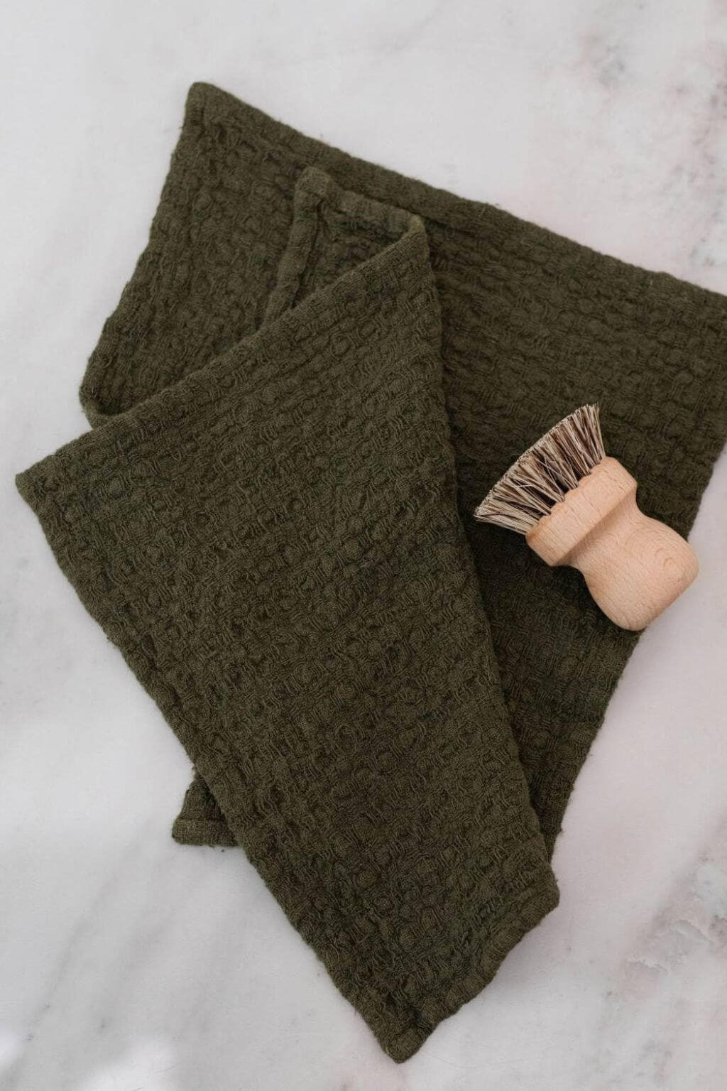 Folded martini olive linen waffle dishcloth with natural wood scrub brush