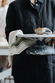 Green stripe linen kitchen towel draped over cake stand during serving