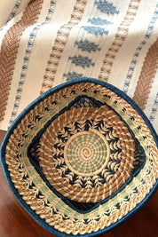 Woven basket with intricate design on a striped fabric background
