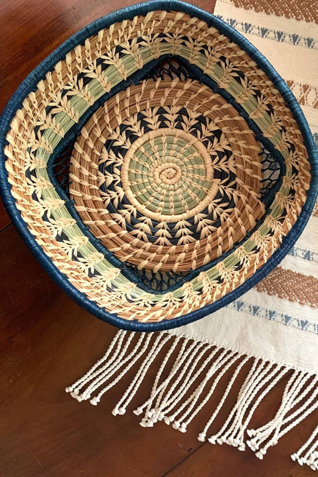 Woven basket with a geometric pattern on a wooden tabletop above a hand woven table runner
