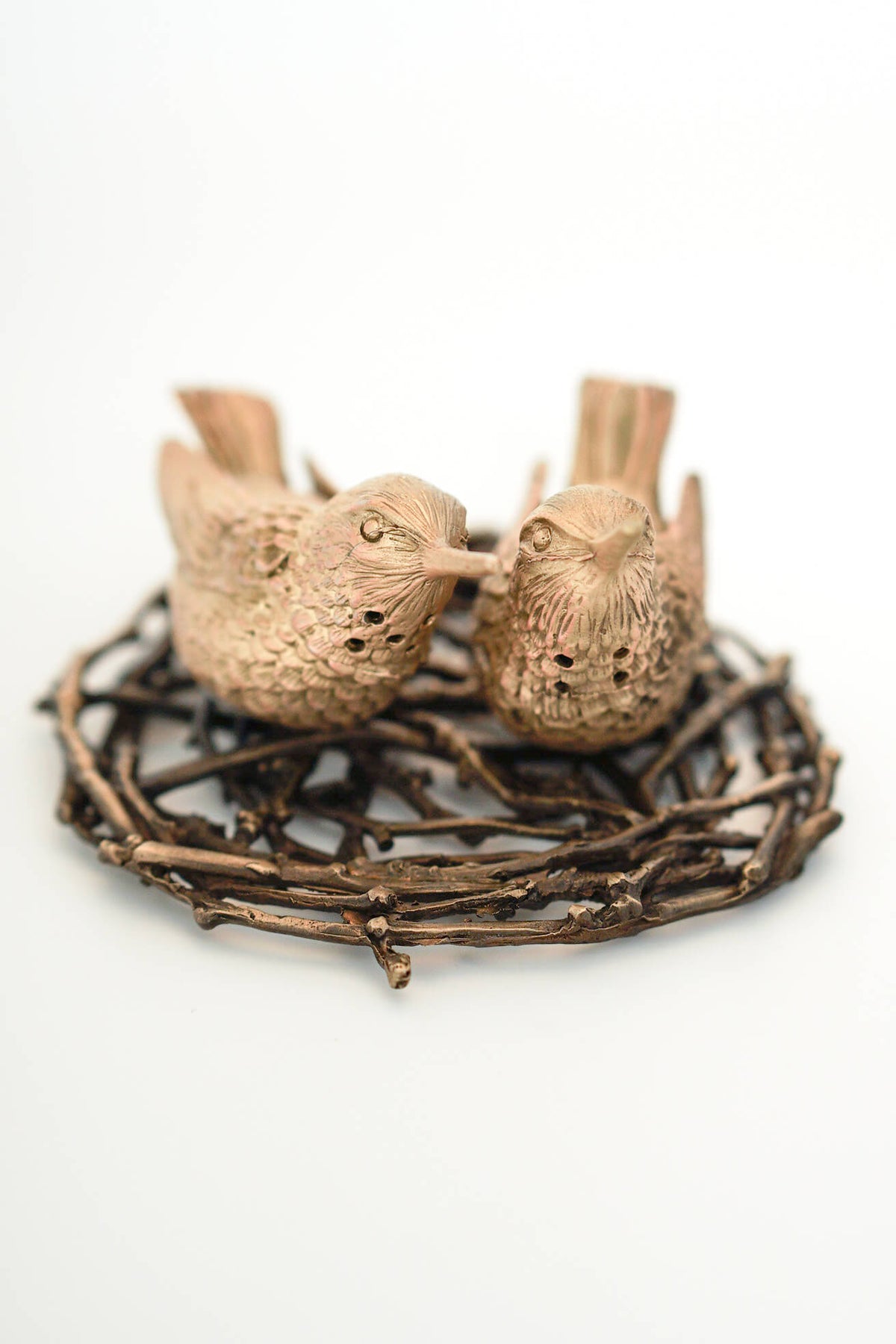 Brass finishs bird salt and paper shakers on a nest tray against a white background