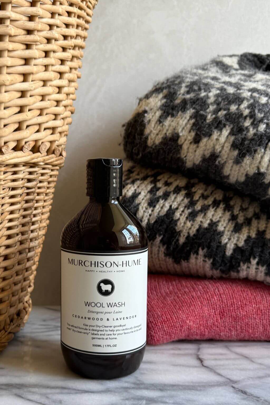Bottle of Murchison-Hume Wool Wash on a marble surface with a textured pillow and woven basket in the background.