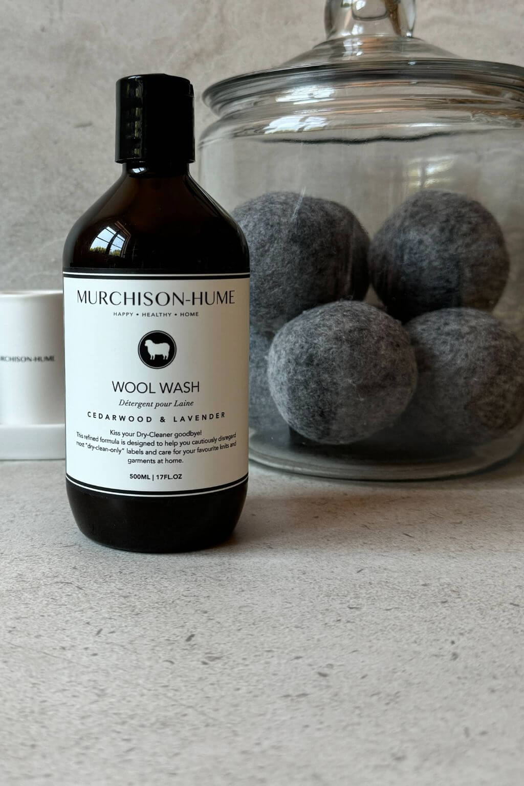 Murchison-Hume wool wash bottle with wool dryer balls in a jar on a neutral background