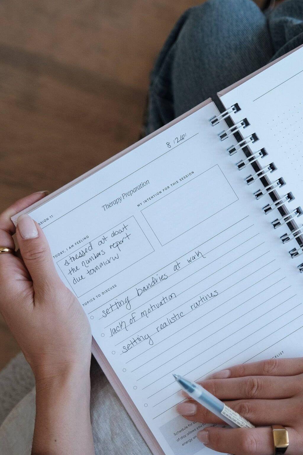 Person holding a spiral-bound notebook for Theraphy Preparation 