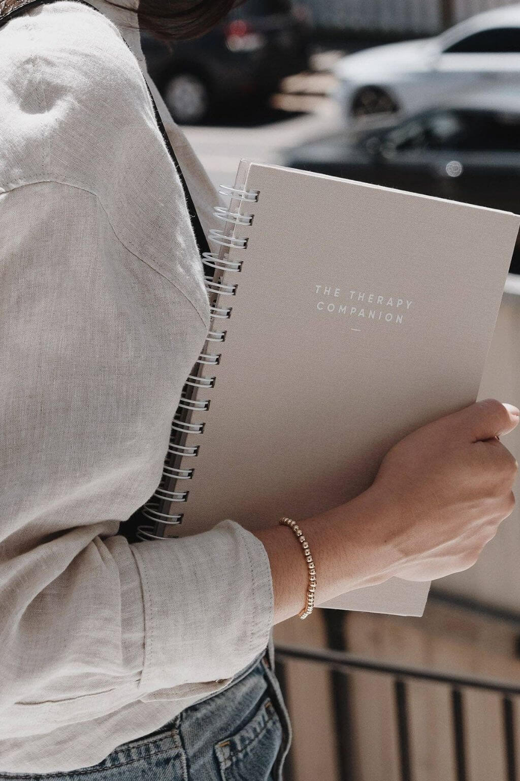 Person holding a spiral-bound notebook titled 'The Therapy Companion'.