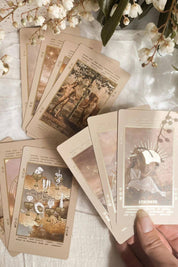 Beige Lucid Dreams Tarot cards held against a white background with floral elements