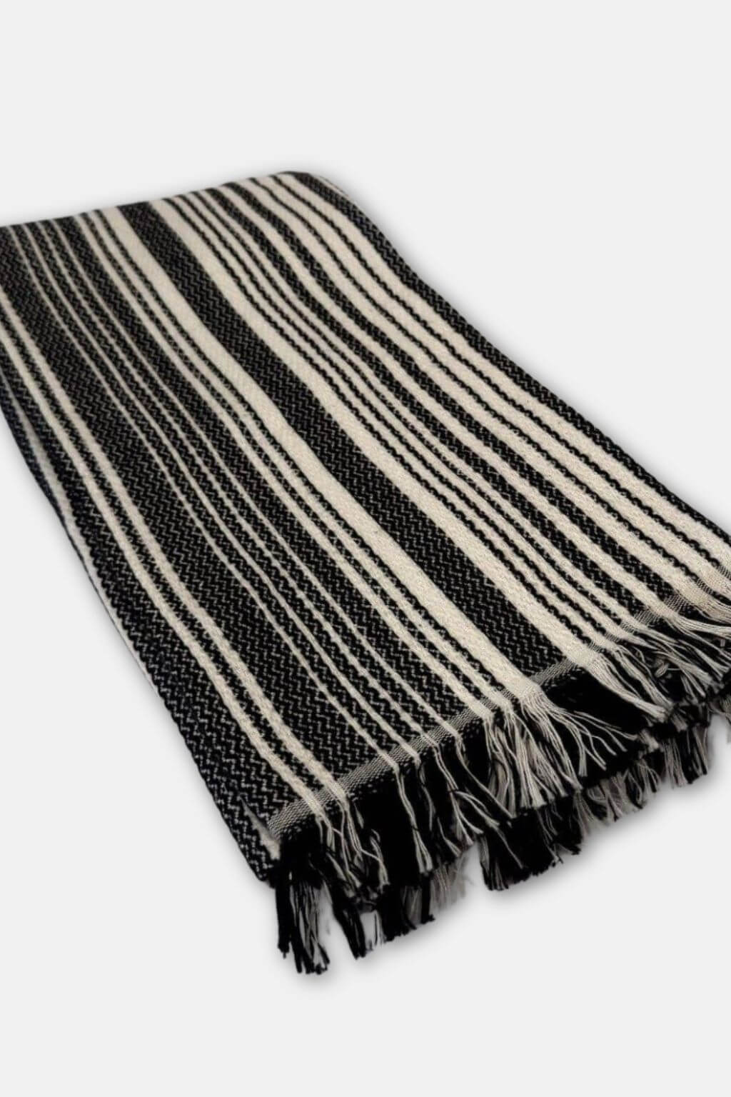 Black and cream striped towel with fringes on a white background