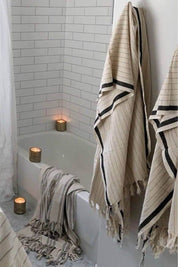 Bathroom with white bathtub, candles, and striped towels.