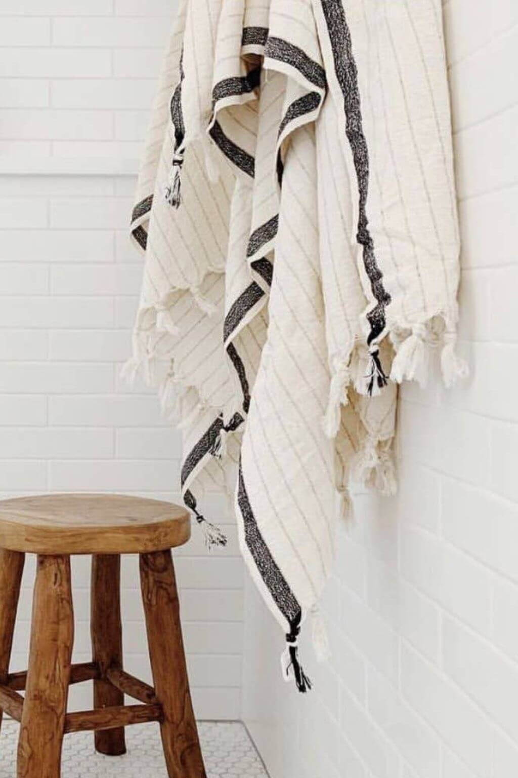 White towel with black stripes hanging on a rack in a bathroom.
