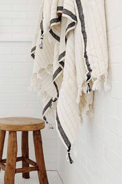 White towel with black stripes hanging on a rack in a bathroom.