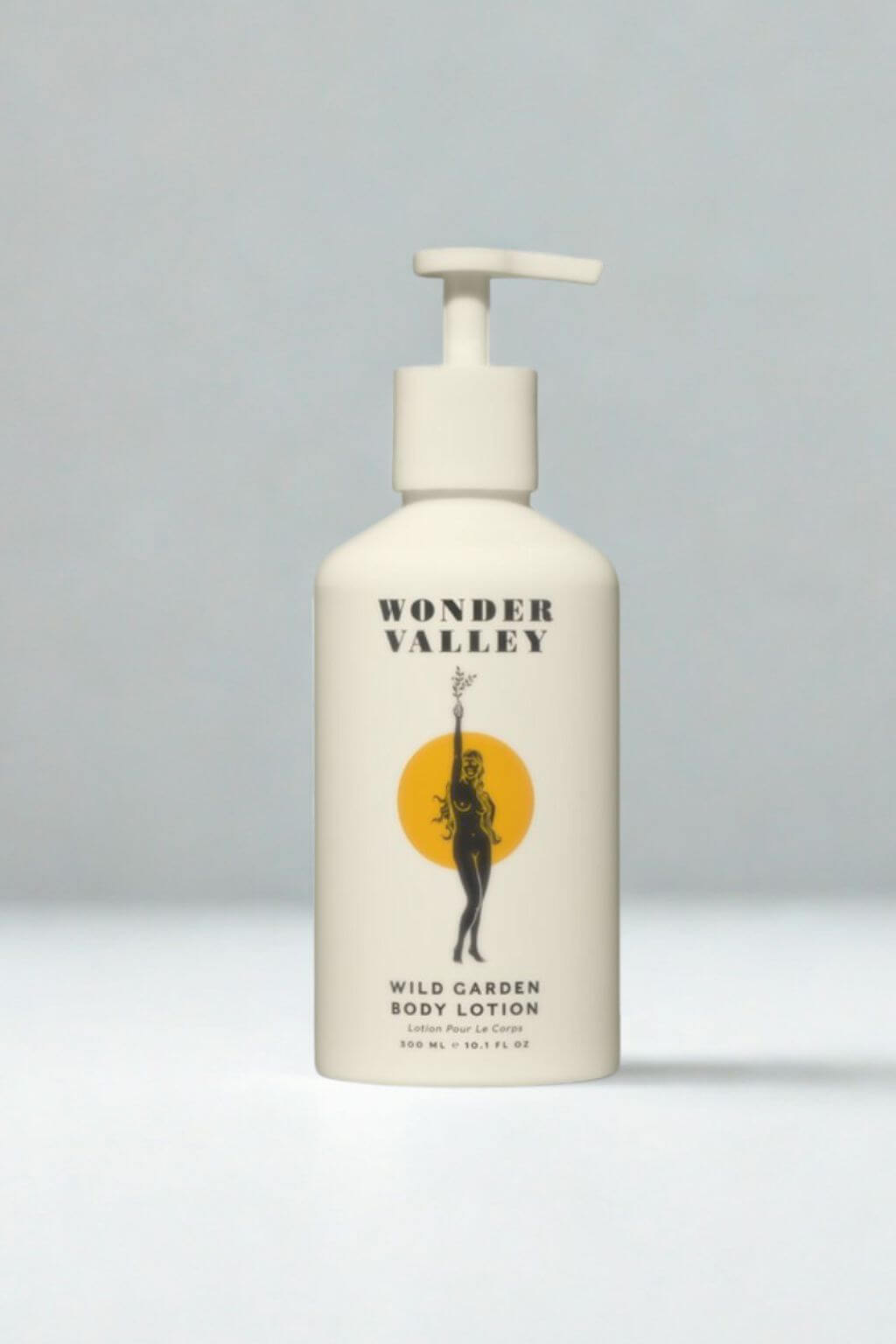 Wonder Valley Wild Garden Body Lotion in a white pump bottle with a black and yellow graphic label, set against a neutral gray background.