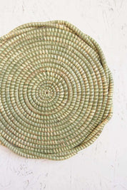 Handwoven sweetgrass trivet with soft green spiral weave and organic scalloped edge