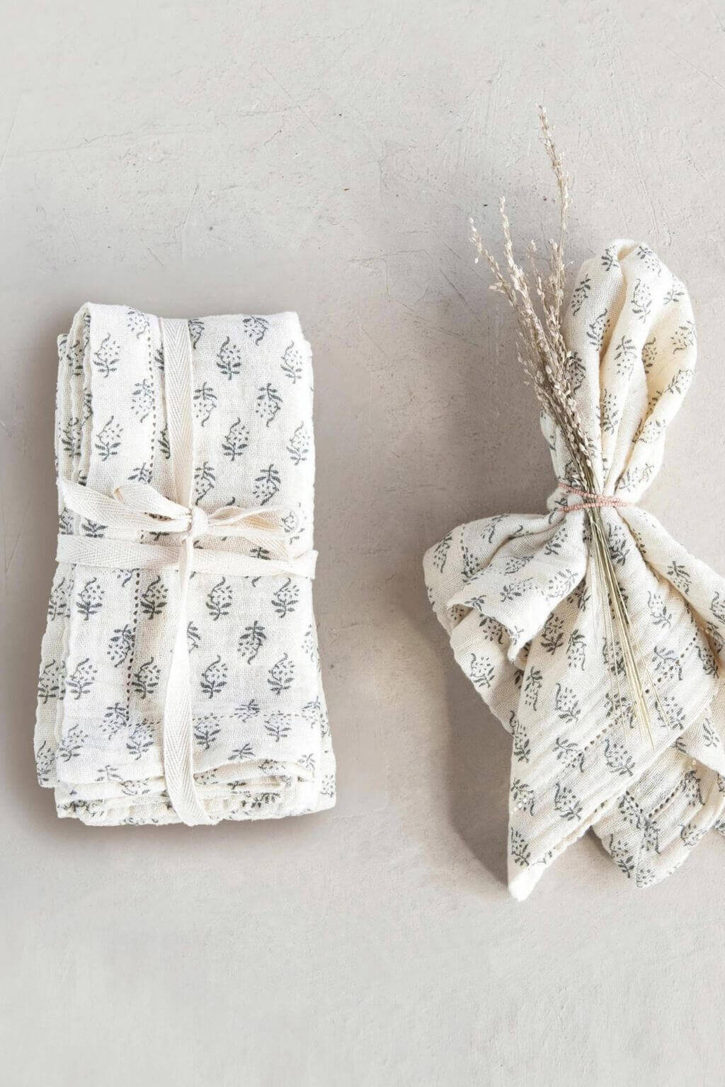 Folded napkins displayed with dried flowers tied in linen ribbon.