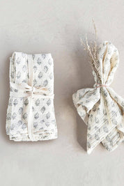 Folded napkins displayed with dried flowers tied in linen ribbon.