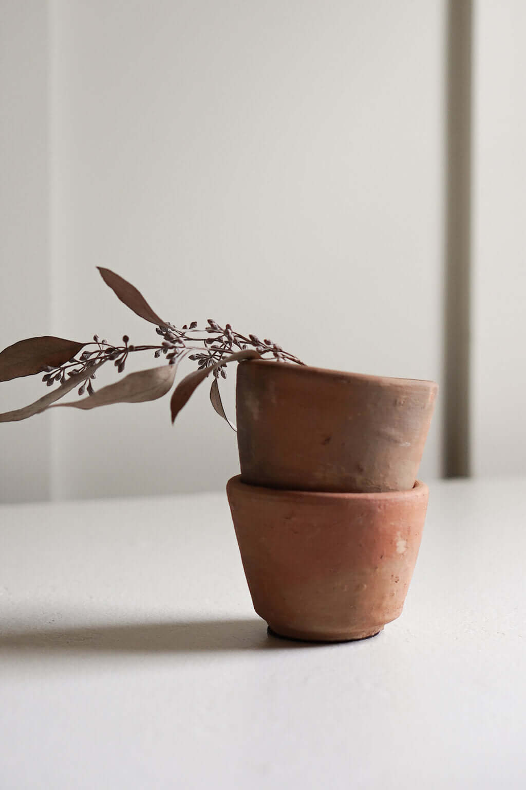 stacked terracotta candle holders with dried foliage