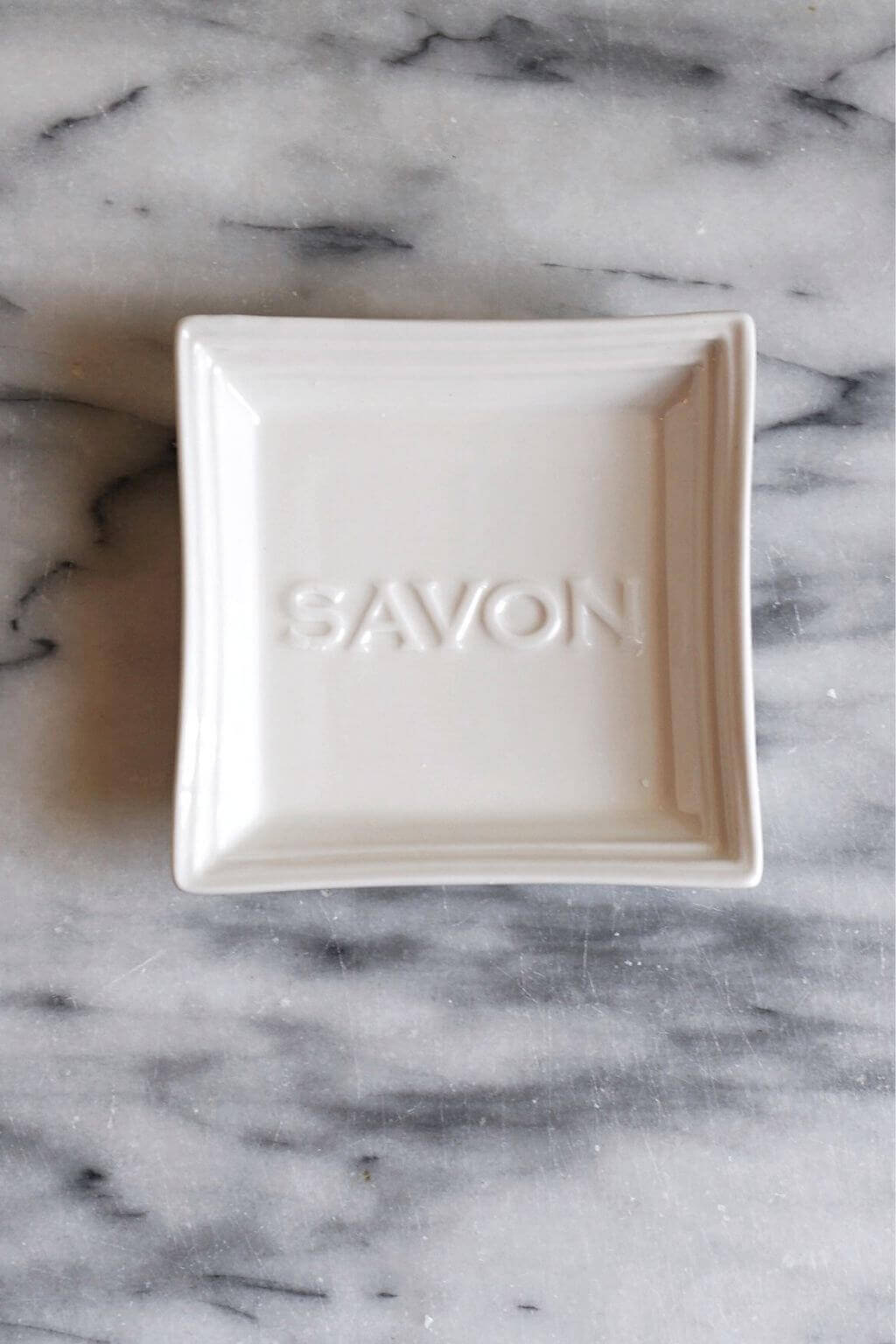 Close-up of embossed "Savon" lettering on ceramic soap dish