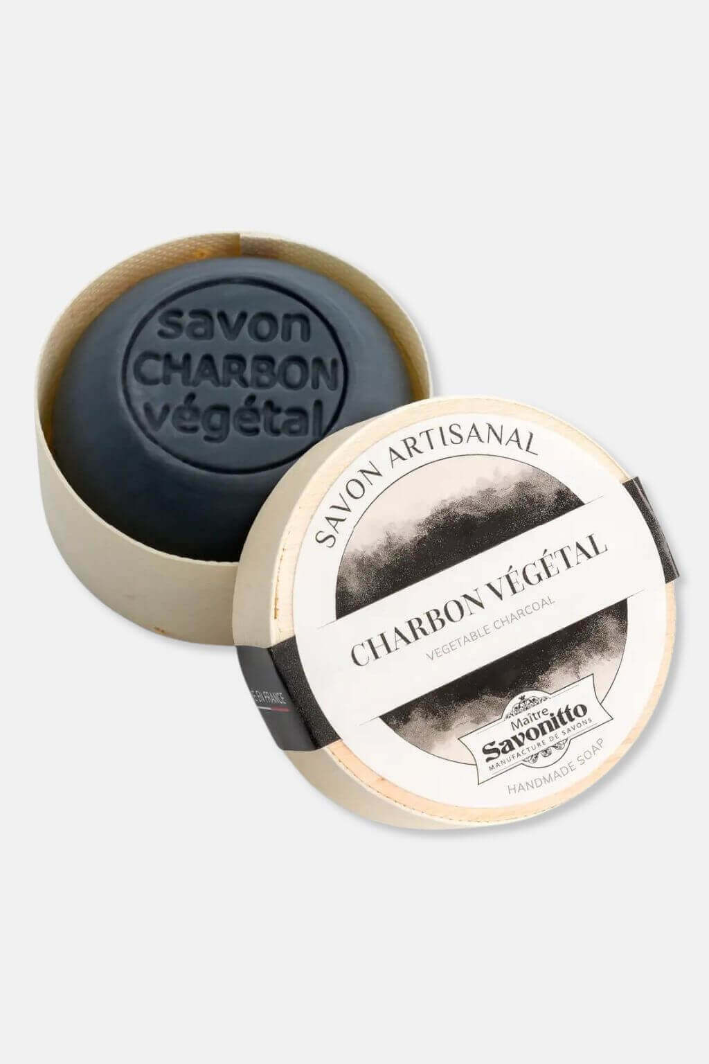 A French charcoal soap with a black and gray marbled pattern, placed inside an open poplar wood box with a label that reads 'Savon Charbon Végétal'.